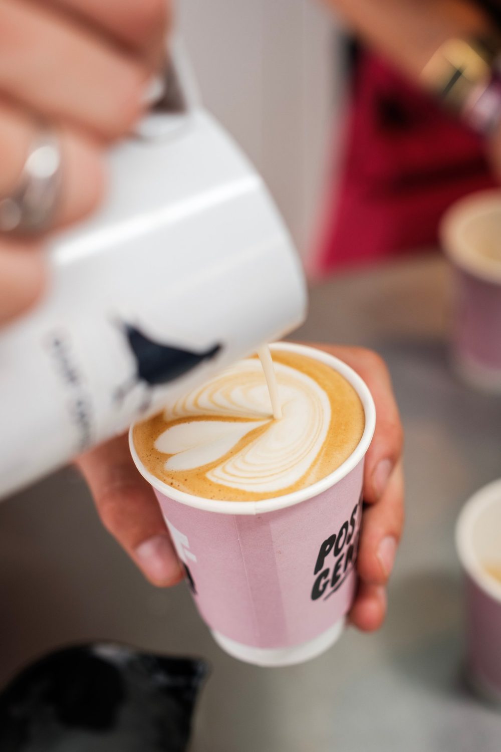 Latte art schenken in een roze to-go-beker